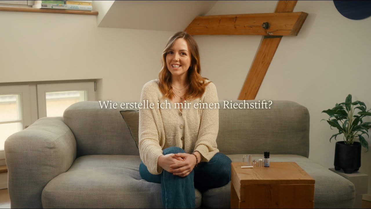 Frau sitzt auf grauem Sofa in hellem Raum mit Holztisch und Aromatherapie Ölen, Galerie Position 1, Schweizer Aromatherapie