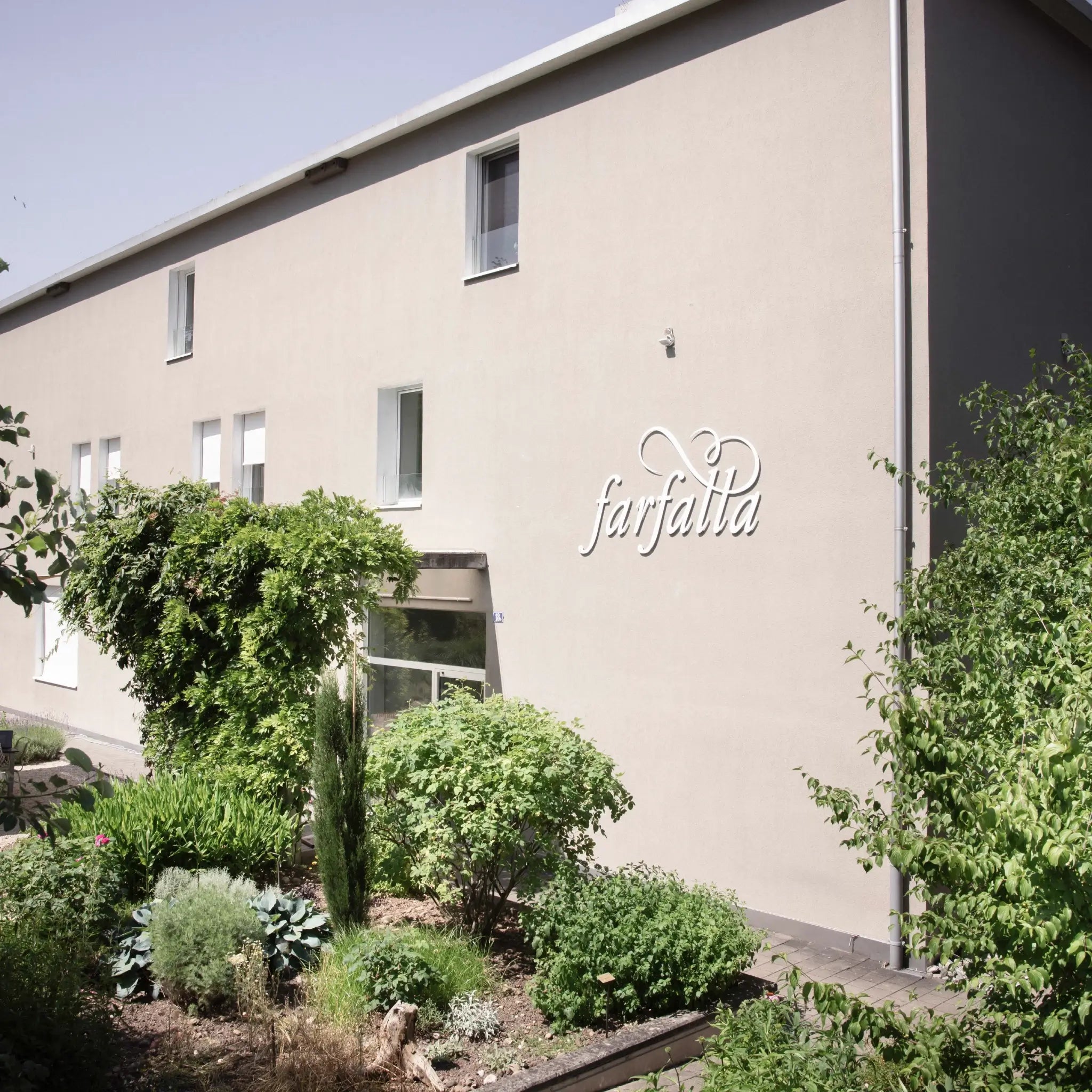 Firmengebäude mit farfalla Logo an der Fassade und gepflegtem Garten, Galerie Position 1, Schweizer Aromatherapie und Naturkosmetik