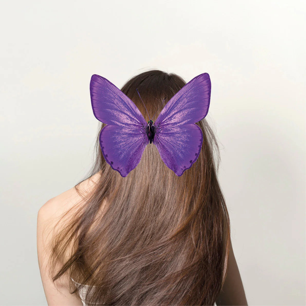 Frau mit langem, braunem Haar und großem, violett schimmerndem Schmetterling auf dem Kopf, Galerie Position 1, Schweizer Aromatherapie