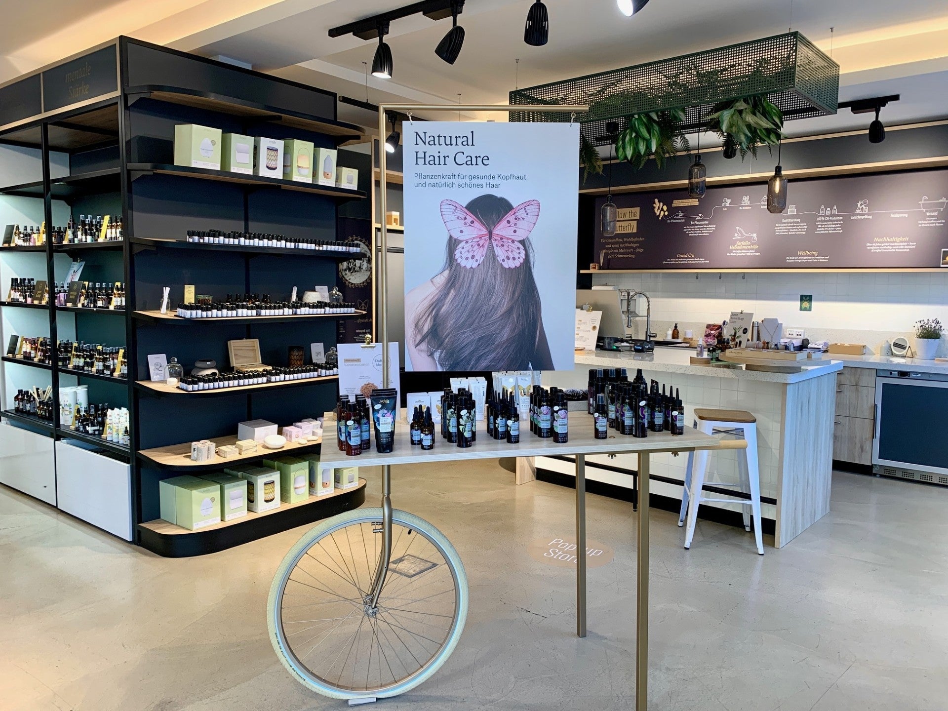 Moderner Verkaufsraum mit natürlicher Haarpflegeausstellung auf Holztablett mit Fahrradrad, Galerie Position 1, Schweizer Aromatherapie.