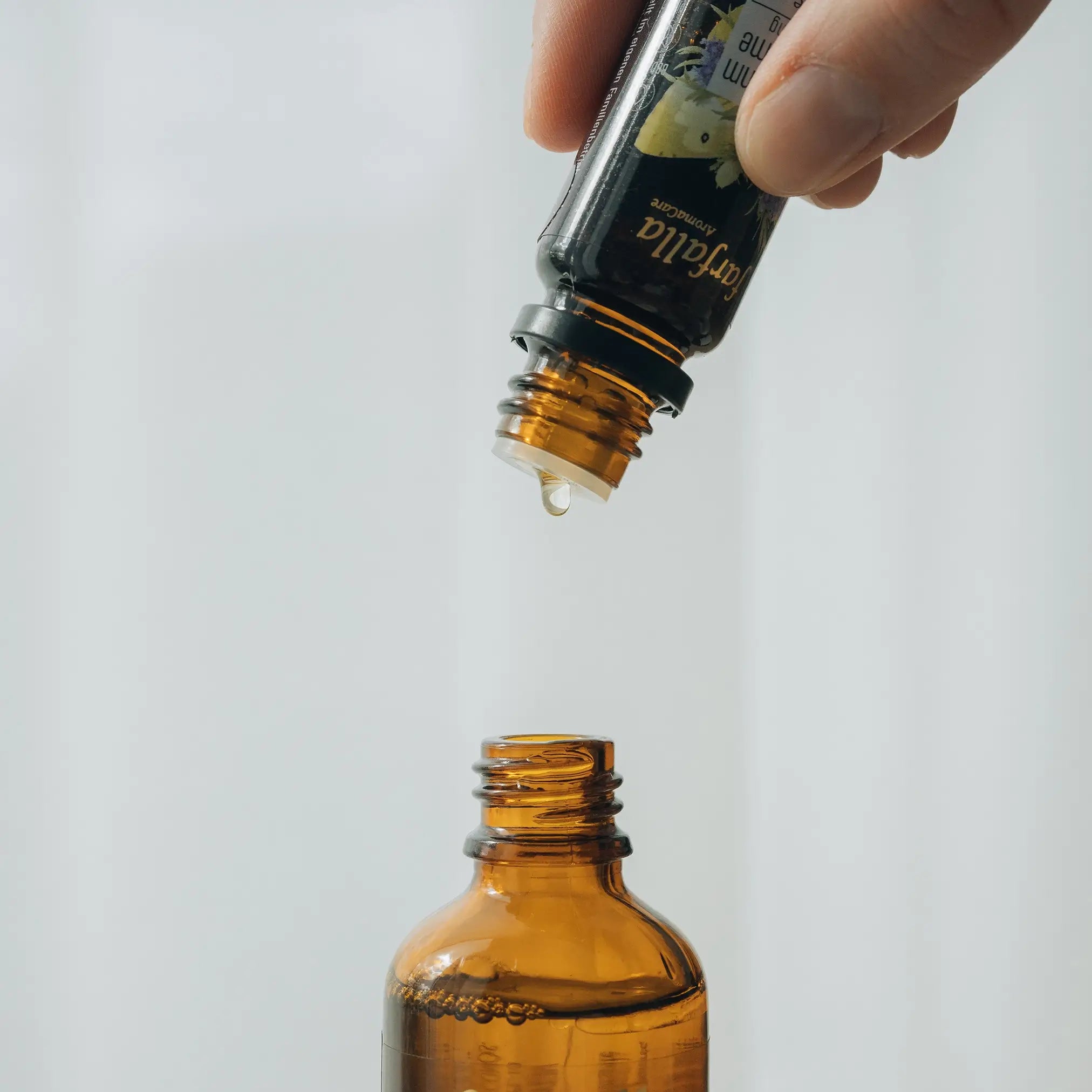 Hand tropft ätherisches Öl in braune Glasflasche, Galerie Position 1, Schweizer Aromatherapie und zertifizierte Naturkosmetik