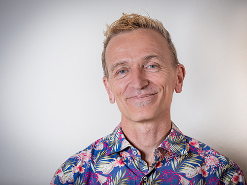 Portrait eines lächelnden Mannes mit buntem Hemd vor hellem Hintergrund, Galerie Position 1, Schweizer Aromatherapie und Naturkosmetik