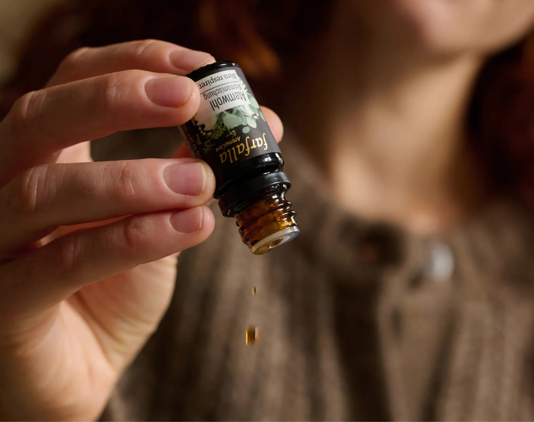 Hand hält Farfalla Aromatherapie-Ölfläschchen, Tropfen fallen, Galerie Position 1, vegane Rezepturen, Schweizer Aromatherapie.