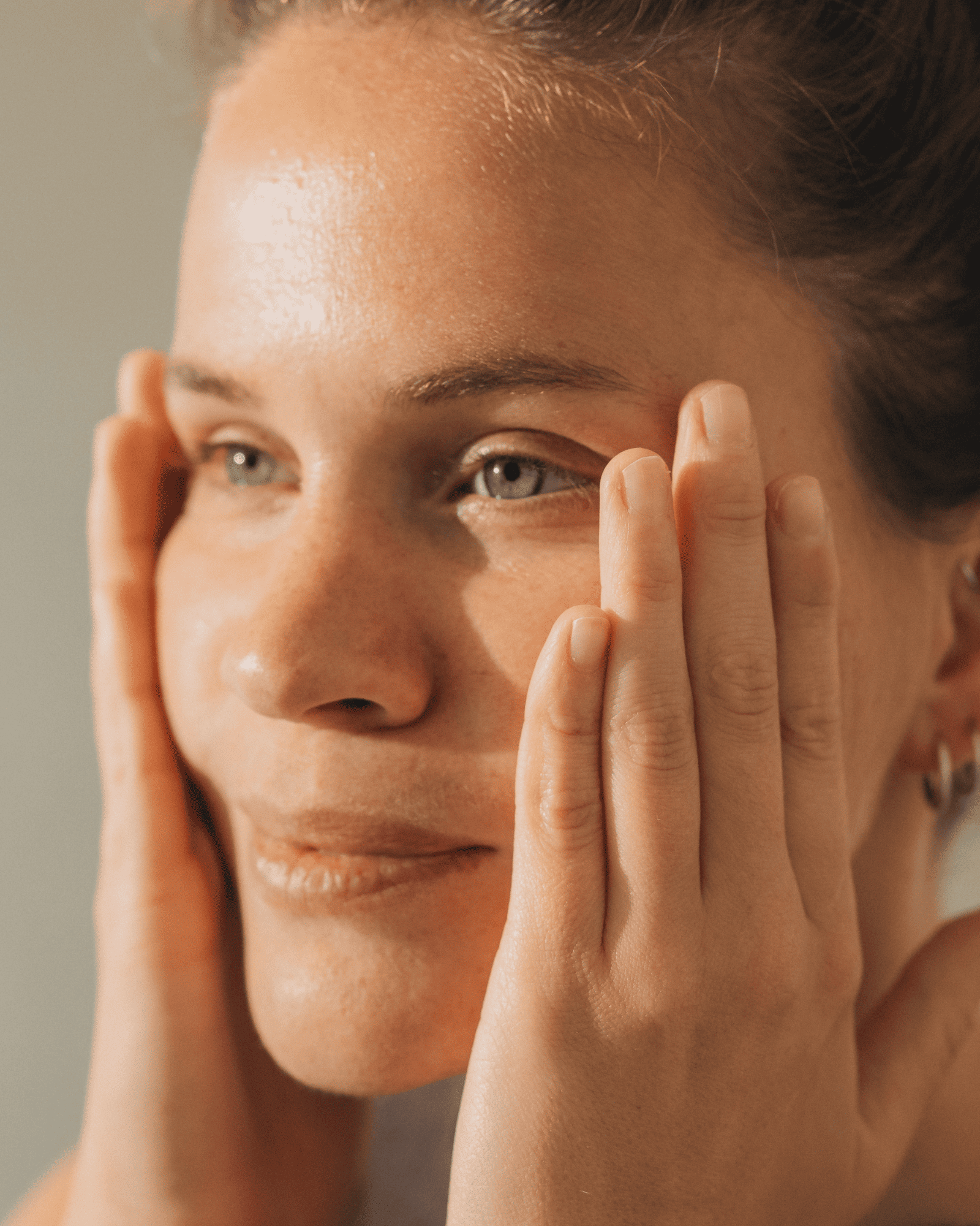 Close-up einer Frau, die sanft ihr Gesicht mit Händen berührt, Galerie Position 1, Schweizer Aromatherapie, vegane Rezepturen