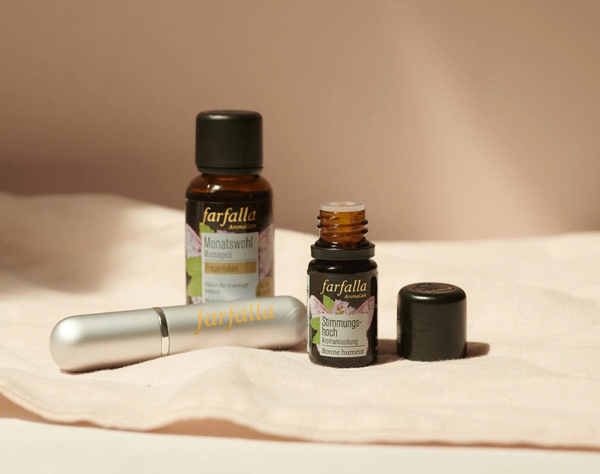 Drei farfalla Aromatherapie-Fläschchen auf hellem Stoff, Galerie Position 1, Schweizer Naturkosmetik mit veganen Rezepturen.