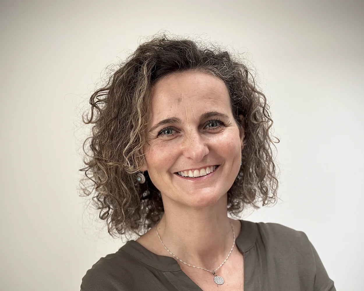 lächelnde frau mit lockigem haar vor hellem hintergrund, galerie position 1, Schweizer Aromatherapie und zertifizierte Naturkosmetik