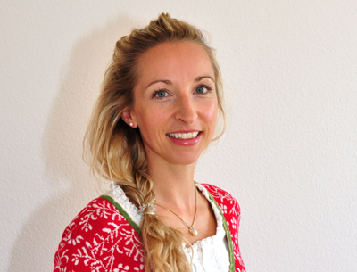 Porträt einer lächelnden Frau mit hellem Zopf vor weißer Wand, Galerie Position 1, Schweizer Aromatherapie und Naturkosmetik