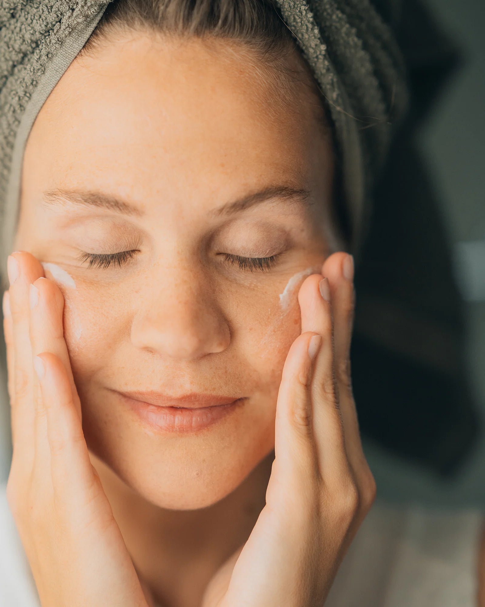 Frau trägt sanft Creme aufs Gesicht auf, Galerie Position 1, Schweizer Aromatherapie, vegane Rezepturen, zertifizierte Naturkosmetik