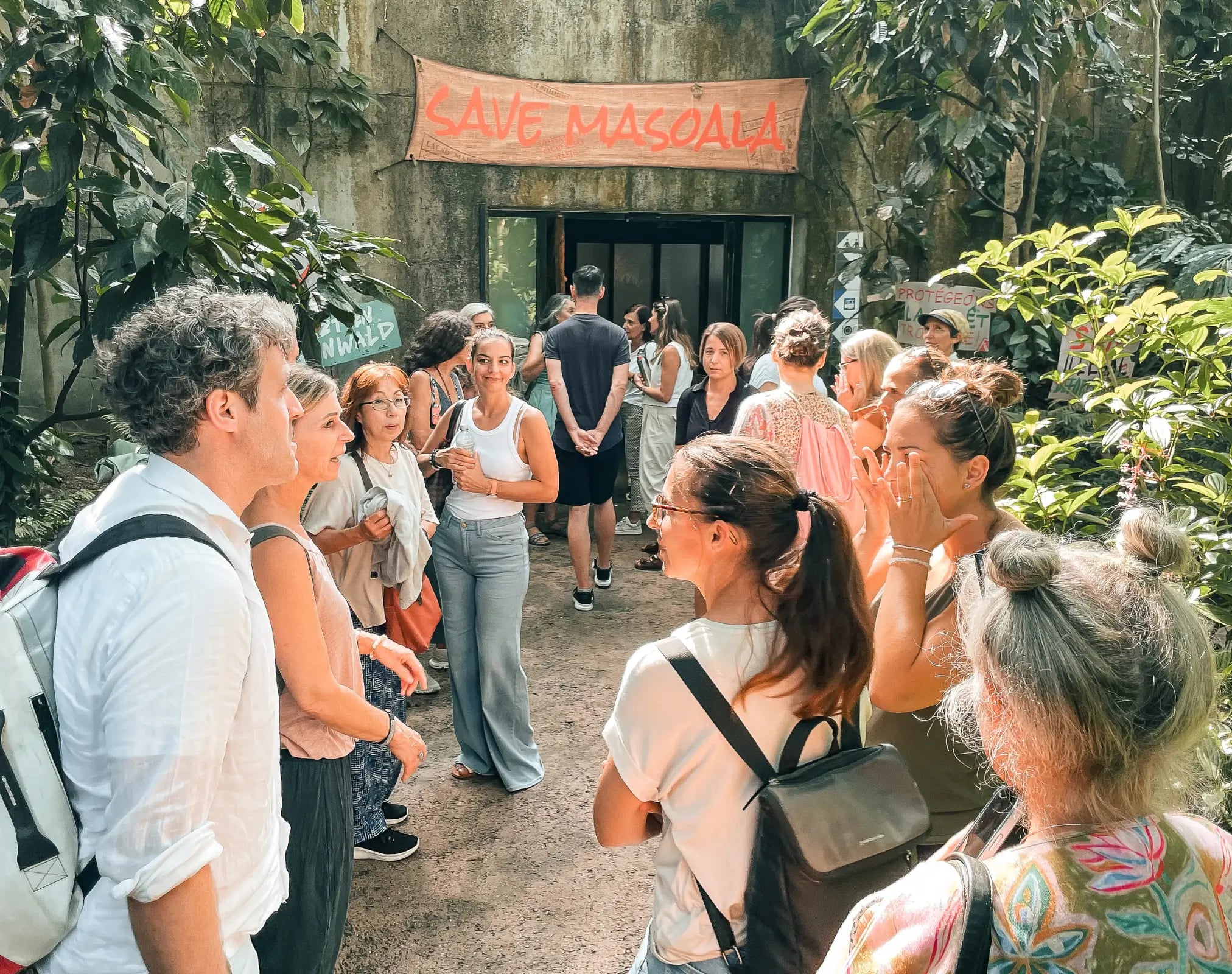 Gruppe von Menschen vor Eingang mit Schriftzug „SAVE MASOALA“, Galerie Position 1, Schweizer Aromatherapie, nachhaltige Herstellung